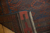Antique Belouch rug's folded corner revealing hand-knotted foundation, deep indigo side, and madder red pile.