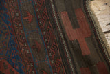 Antique Belouch rug detail: charcoal ground with madder red, indigo geometric patterns and fringe.