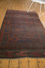 Secured end detail of the antique Belouch rug, with rich geometric bands and indigo, red medallions.