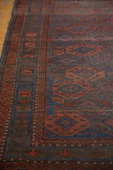 Antique Belouch rug with geometric medallions, intricate border, madder red, indigo blue, charcoal brown.