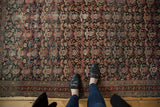 Antique Malayer rug's charcoal field, allover boteh, intricate vinery, localized wear, tattered selvage.