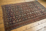 Corner of antique Malayer rug, intricate charcoal and blush boteh pattern, traditional borders, tattered selvage.