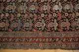 Intricate interlaced boteh design and wear on antique Malayer rug's charcoal field and red border.