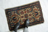 Persian Borchalou rug corner detail: tattered edge, navy border, ivory floral scroll.