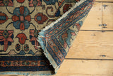 Hand knotted Persian Borchalou rug, revealing foundation, tattered fringe, and ivory field with red, blue florals.