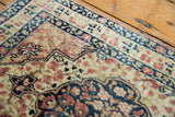Delicate floral vinery and low pile texture on the corner of an antique Persian Kerman rug.
