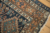 Karaja rug corner with navy, terracotta, sky blue geometric patterns, visible wear, and secured edge.