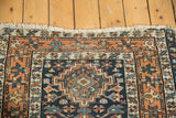 Frayed fringe and worn geometric border in terracotta and cream on a navy blue Karaja rug.