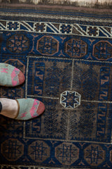 Antique Belouch rug with contrasting indigo blue and charcoal geometric motifs, ivory accents.