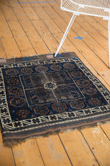 Antique Belouch rug's indigo and charcoal geometric field, showing pile etching and tattered end.