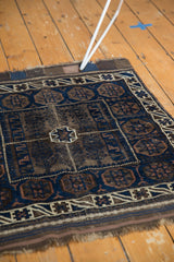 Detail of antique Belouch bag face rug, tattered fringe and rich indigo, brown geometric motifs.