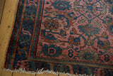 Dusty rose Herati pattern, blue border, and worn fringe on a Lilihan vintage rug.