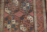 Vintage Belouch rug close-up: geometric gul motifs, madder red, sky blue, and visible knot wear.