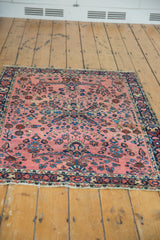 Curled edge of vintage Mohajeran Sarouk rug, displaying dusty raspberry field and floral motifs.