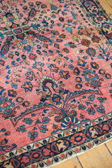 Close-up of vintage Sarouk rug's low pile, dusty raspberry field, and intricate floral border.