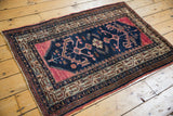 Vintage Hamadan rug corner with navy field, raspberry mahi motifs, and ivory geometric border.
