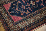 Vintage Persian Hamadan rug corner, showing navy blue field, raspberry red panel, and worn pile.