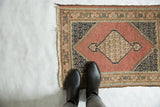 Worn dusty rose field and navy floral boteh spandrel on a vintage Tabriz rug.