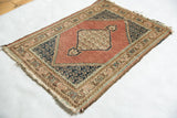 Corner of vintage Tabriz rug with navy floral botehs, dusty rose field, and detailed multi-toned border.