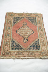 Vintage Tabriz rug corner: dusty rose field, navy floral spandrel, and tattered end.