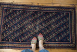 Antique Belouch rug's unusual germinating flower motif; navy, madder red, ivory, showing visible wear.