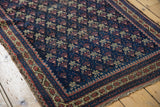 Antique Belouch rug corner, showing blue field with germinating flower motif and floral border.