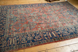 Corner of vintage Persian Mahal rug showing intricate indigo border and brick red floral field.
