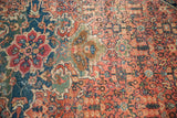 Detail of antique Farahan Sarouk rug with terra cotta, navy, green palmettes, and aged patina.