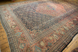Antique Farahan Sarouk carpet featuring dramatic terra cotta medallion and intricate abrash-rich navy field.