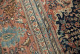 Farahan Sarouk rug detail: ornate floral patterns, terra cotta, navy, soft green, low pile, visible foundation.