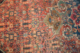 Antique Farahan Sarouk carpet's intricate floral palmettes and vines in time-softened rust, navy, and green.