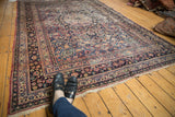 Intricate floral palmettes, vinery, and border details on vintage Persian Meshed carpet in blue, red, and ivory.