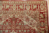 Corner of a vintage Tabriz rug showing its serrated border design in rust and sand tones.