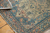 Haji Jalili Tabriz rug border detail with intricate dusty teal, rose, and ivory patterns, worn.