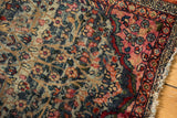 Vintage Kerman rug detail showing abrash, botanical field, intricate border, and frayed fringe.