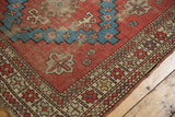 Geometric brick red, aqua blue, and ivory patterns on an antique Caucasian rug, showing even wear.