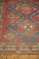 Antique Caucasian geometric border and worn red field with aqua and ivory motifs.