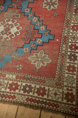 Antique Caucasian rug corner with brick red field, aqua blue geometrics, and ivory patterned border.