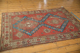 Antique Caucasian rug corner, featuring geometric borders and brick red with aqua patterns.
