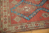 Geometric patterns in rich brick red, aqua blue, and ivory on an antique Caucasian rug.