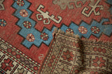 Antique Caucasian rug: hand-knotted foundation, fringed edge, and geometric pile in brick red, aqua blue.