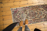 Vintage Kerman runner, worn rococo floral in ivory, red, blue, full view with feet.