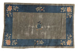 Antique Peking rug with worn gray-green field, deep blue border, and central, corner florals.