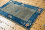 Antique Peking rug corner: traditional coral florals on cobalt blue border, worn slate gray field.
