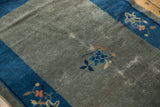 Antique Peking rug's slate blue-gray field, cobalt border, floral motifs, and localized foundation wear.