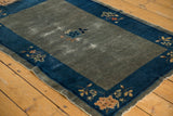 Peking rug corner with worn slate blue-gray field, cobalt border, and tan floral motif.