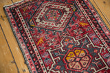 Detail of the vintage Karaja runner's geometric pattern in cherry red, saffron yellow, and mallard green with secured edge.