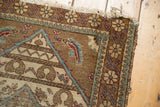 Tattered corner of Vintage Sparta rug, with Mahi spandrel, floral border, and worn field.