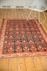 Vintage Malayer rug's repeating floral design in dark navy charcoal, tangerine, and blush.
