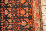 Vintage Malayer rug showing dark navy floral pattern, contrasting floral border, and light tattered fringe.